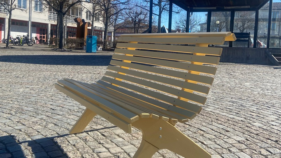 En gul bänk på ett torg. Foto 