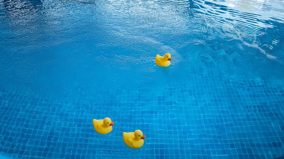 Tre gummiankor flyter i en blå pool