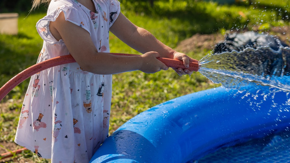 Flicka i klänning som fyller en pool. Foto 
