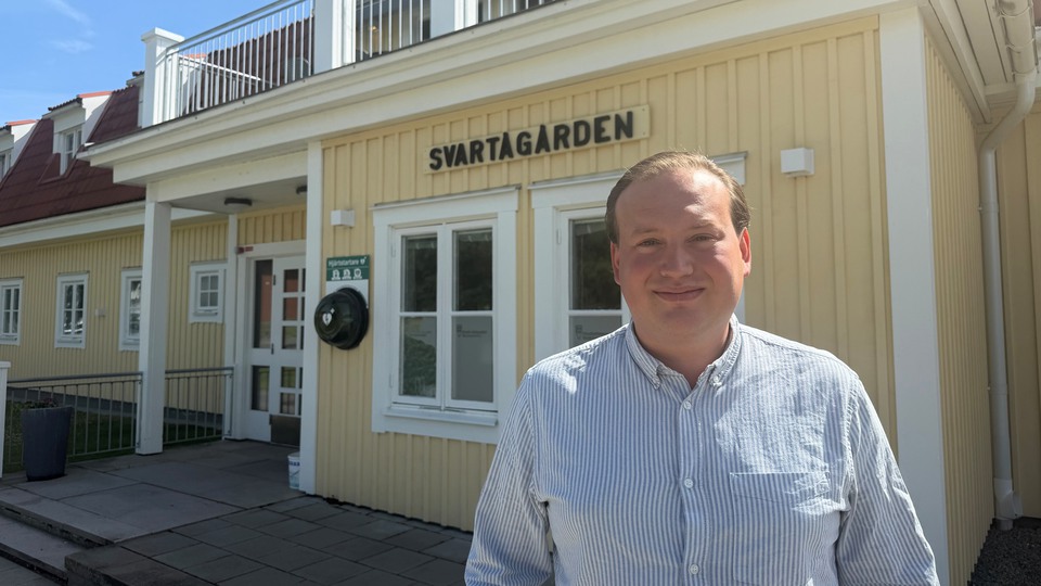 Man som står framför en gul byggnad med texten "Svartågården" på. Foto 