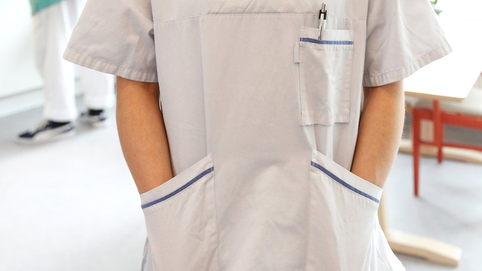 Undersköterska med händerna i fickorna. Foto 