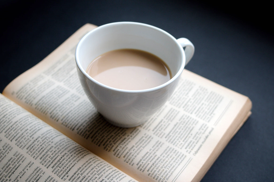 Tekopp placerad på öppen bok. Fotorealistisk. AI-genererad. 