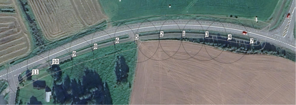 Flygfoto över en landsväg med markerade cirklar och numrering från 1 till 11 längs ena sidan av vägen. Numreringen visar placeringen av planerade belysningspunkter. Foto