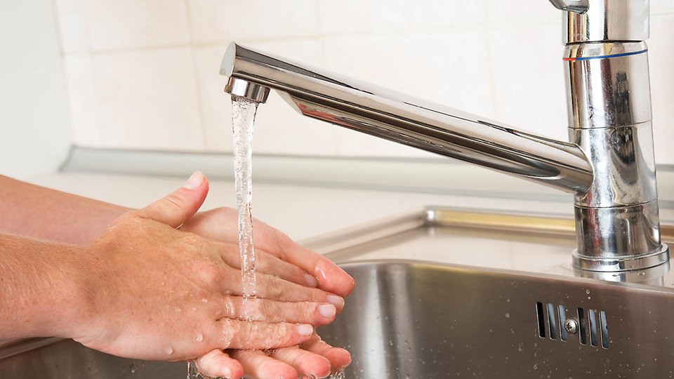 Händer som tvålar in sig vid rinnande vatten från en kran. 