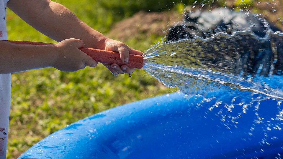 Liten flick asom fyller en pool med vatten. Foto 